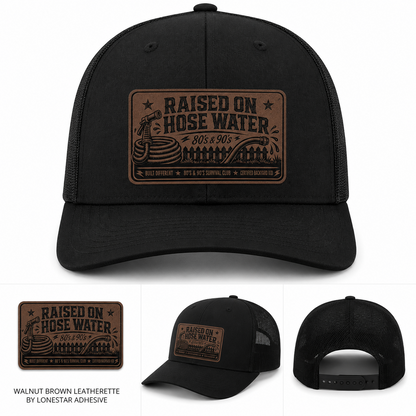 Black trucker hat with walnut brown leatherette patch engraved with Raised on Hose Water 80’s and 90’s design